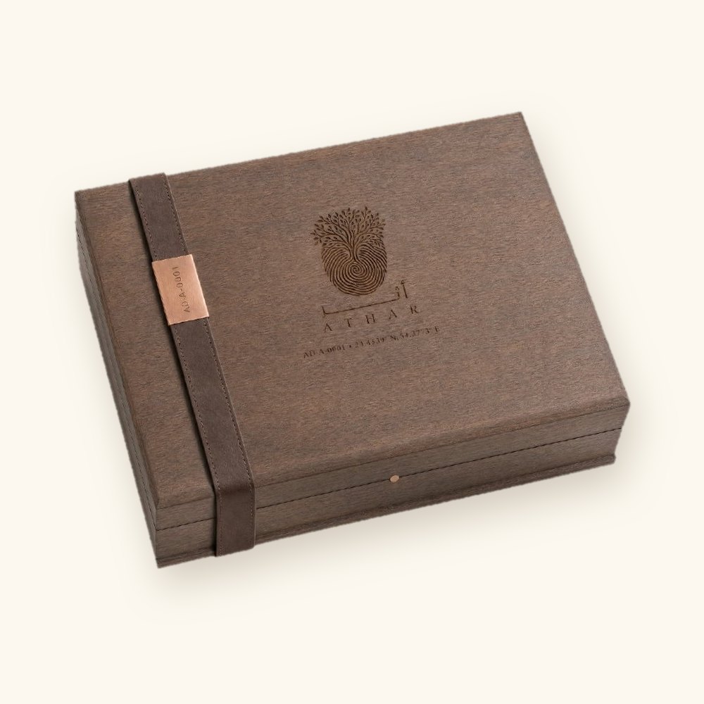 The ATHAR Legacy heritage walnut box, closed, with an engraved mark and a copper ID plate on its strap